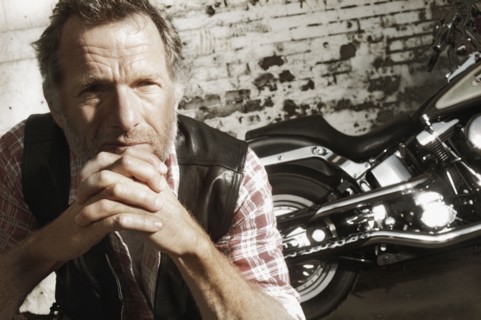 Mature man in front of motorcycle. Photographe : Stewart Cohen