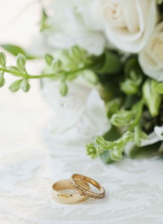 Two wedding rings by bouquet of flowers, studio shot. Photographe : Jamie Grill