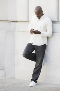 Man text messaging outside office building. Photographe : PT Images