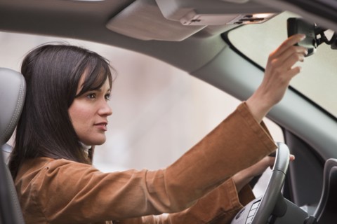 Woman adjusting rear view mirror.