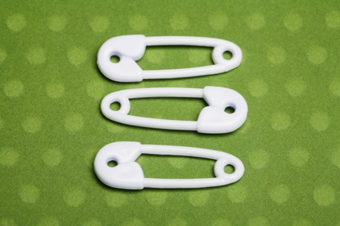 Three safety pins. Photographe : Kristin Lee