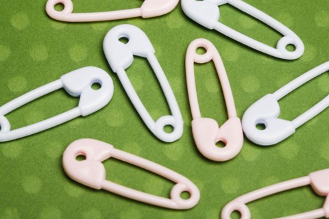 Safety pins on green background. Photographe : Kristin Lee