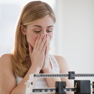 Young woman using measuring scales. Photographe : Daniel Grill