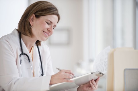 Female doctor writing on clipboard.