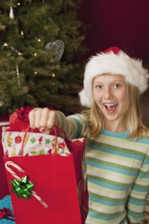 Teenage girl (13-15) wearing Santa hat holding Christmas gift. Photographe : Sarah M. Golonka