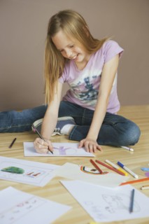 Girl (10-12) sitting on floor and drawing pictures. Photographe : Sarah M. Golonka
