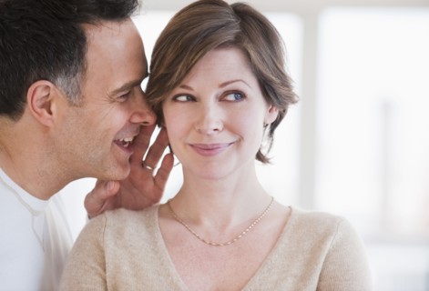 Man whispering to woman's ear.