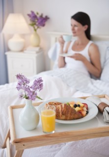A man bringing a woman breakfast in bed.