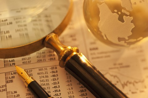 A magnifying glass globe and pen on paperwork.