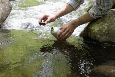 A man with a reusable water bottle in the woods