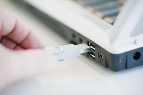 A hand plugging in a universal serial bus.
