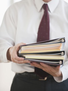 Businessman carrying binders.