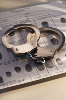 Hand cuffs on a page of fingerprints