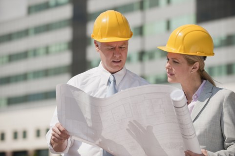 Two architects holding plans outdoors.