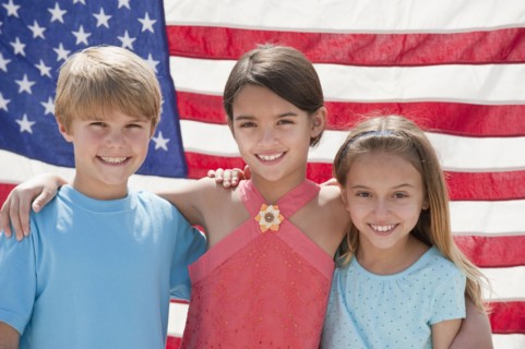 Three children in front of an American flag.