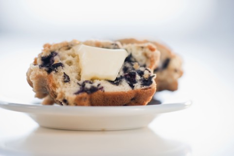 A blueberry muffin with butter.