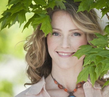 A woman outdoors surrounded in greenery.