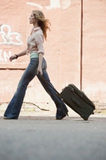A woman walking with a suitcase.