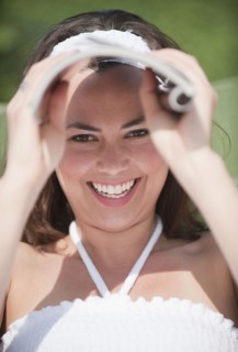 A woman outdoors shielding her eyes with a magazine.