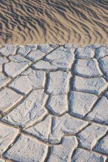 Sand dunes in the desert with cracked earth.