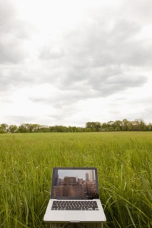 A computer in a field with an image of a city