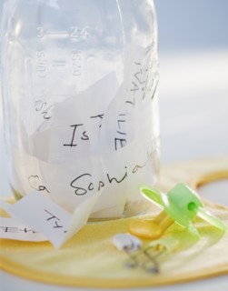 A baby bottle full of baby names beside a pacifier