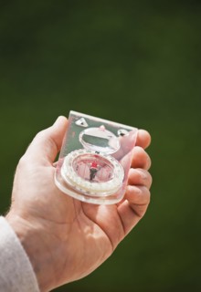 A hand holding a compass.