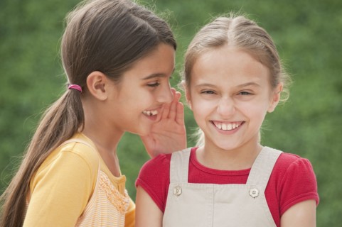Two girl friends whispering.