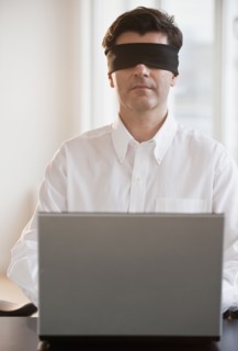 Businessman using laptop while blindfolded.