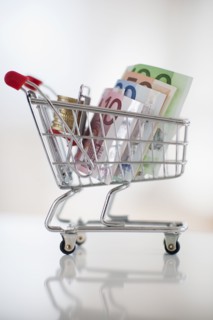 A miniature shopping cart with bank notes and coins.