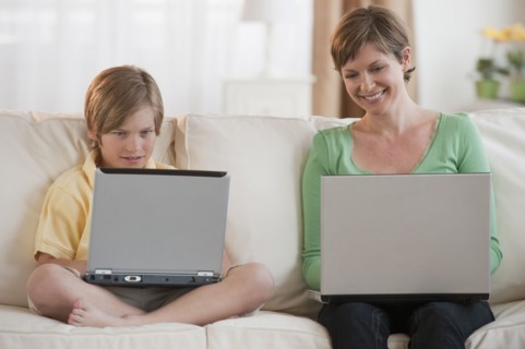 Mother and son on laptops.