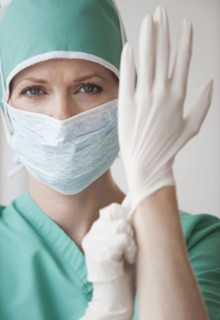 Female doctor putting on gloves.