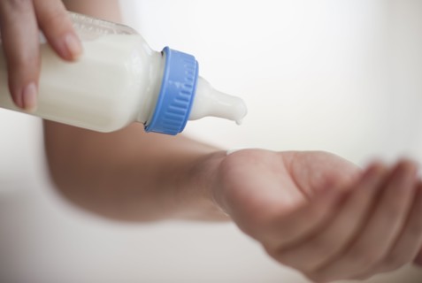 Hands holding baby bottle.