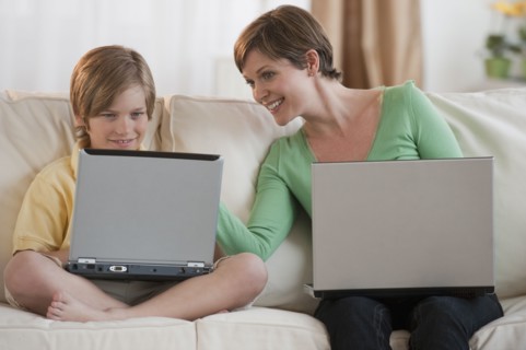 Mother and son on laptops.