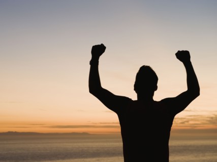 Silhouette of man raising arms