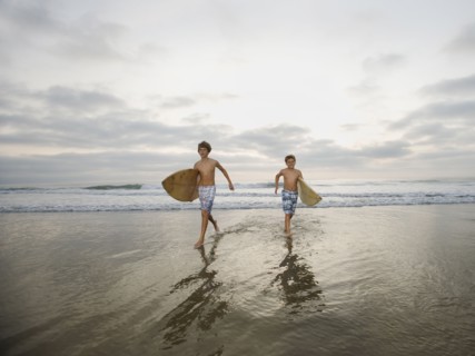 Boys running with surfboards