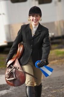 Jockey walking with saddle and ribbon.