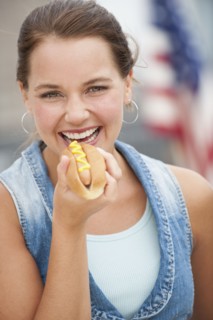 Woman eating hotdog.