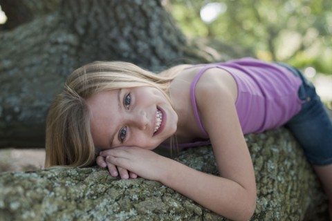 Girl lying down on tree