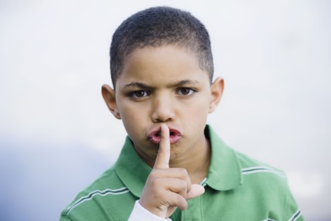 Boy with finger in front of mouth