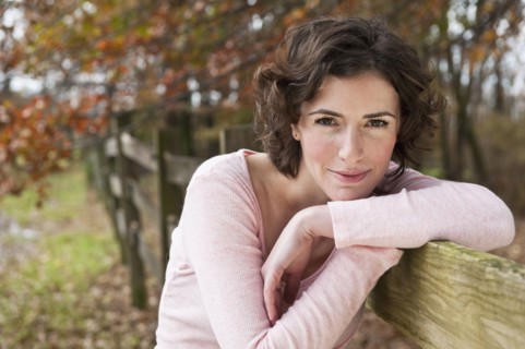 Woman leaning on fence.