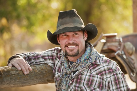 Cowboy leaning on fence.