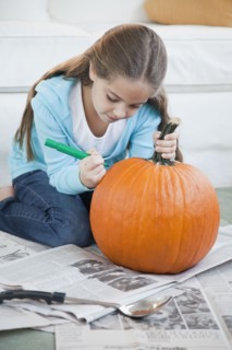 Young girl drawing on pumpkin. Photographer: Jamie Grill