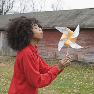Girl blowing toy windmill. Photographer: Pauline St.Denis
