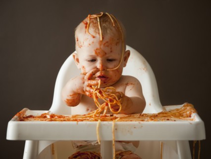 Baby covered in spaghetti. Photographer: Mike Kemp