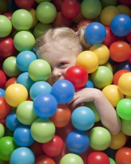 Girl hiding under balls. Photographer: Mike Kemp