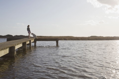 Woman and dog on pier. Photographer: Chris Hackett