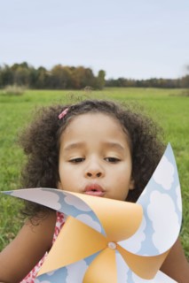 Young girl blowing toy windmill. Photographer: Pauline St.Denis