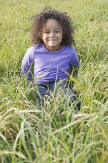 Young girl sitting in tall grass. Photographer: Pauline St.Denis