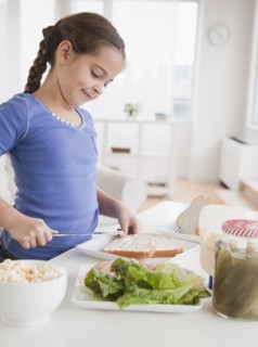 Young girl making sandwich. Photographer: Jamie Grill